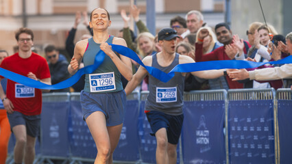  Portrait of Athletic Female Jogger Crossing the Finish Line in Marathon Race with the Audience Cheering. Happy Successful Woman Celebrating Winning, Feeling Empowered with her Achievement 