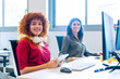 Two smiling women with headphones in a collaborative office environment. 