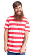 Handsome young red head man with long beard wearing casual clothes winking looking at the camera with sexy expression, cheerful and happy face.