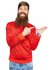 Wall Mural - Redhead man with long beard wearing casual clothes amazed and smiling to the camera while presenting with hand and pointing with finger.