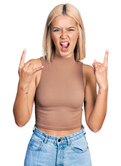 Canvas Print - Beautiful young blonde woman wearing casual style with sleeveless shirt shouting with crazy expression doing rock symbol with hands up. music star. heavy concept.