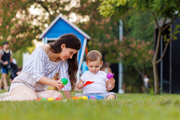 Wall Mural - Mother and toddler boy playing in the park while having picnic