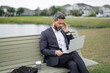 © Volodymyr - Stressed business man in suit sitting on bench. Stressed ceo manager work on laptop. Business man have stress and headache. Head pain migraine. Tired freelancer man online work from laptop in park.