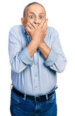 Poster - Senior man with grey hair and beard wearing casual blue shirt shocked covering mouth with hands for mistake. secret concept.