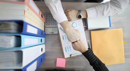 Wall Mural - Businessmen touching their fists at table top view. Profitable partnership work concept