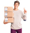 © Krakenimages.com - Young handsome man holding delivery package surprised with an idea or question pointing finger with happy face, number one
