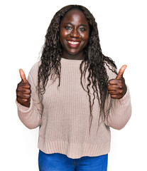 Poster - Young african woman wearing wool winter sweater success sign doing positive gesture with hand, thumbs up smiling and happy. cheerful expression and winner gesture.