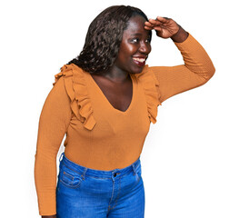 Poster - Young african woman wearing casual clothes very happy and smiling looking far away with hand over head. searching concept.