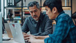 © Moritz - Engaged Mid-Aged Latin Manager Mentoring Eager Young Asian Employee on a Project with Laptop in Sunlit Office - Diverse Business Collaboration Scene