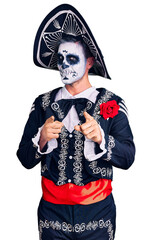 Canvas Print - Young man wearing day of the dead costume over background pointing fingers to camera with happy and funny face. good energy and vibes.