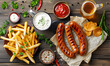 Appetizing roasted sausages with fries and sauces on the wooden table. Top view. Edited AI illustration.