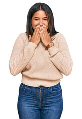 Canvas Print - Young latin girl wearing wool winter sweater laughing and embarrassed giggle covering mouth with hands, gossip and scandal concept