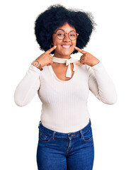 Wall Mural - Young african american girl wearing casual clothes and glasses smiling with open mouth, fingers pointing and forcing cheerful smile