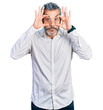 © Krakenimages.com - Middle age hispanic with grey hair wearing casual white shirt trying to open eyes with fingers, sleepy and tired for morning fatigue