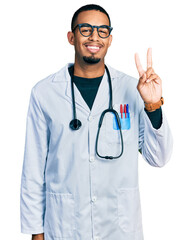 Wall Mural - Young african american man wearing doctor uniform and stethoscope showing and pointing up with fingers number two while smiling confident and happy.