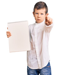 Poster - Cute blond kid holding notebook pointing with finger to the camera and to you, confident gesture looking serious