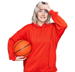 Sticker - Young blonde girl holding basketball ball stressed and frustrated with hand on head, surprised and angry face