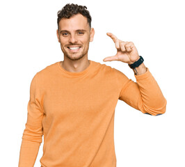 Sticker - Young hispanic man wearing casual clothes smiling and confident gesturing with hand doing small size sign with fingers looking and the camera. measure concept.