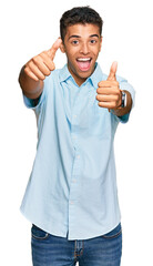 Wall Mural - Young handsome african american man wearing casual clothes approving doing positive gesture with hand, thumbs up smiling and happy for success. winner gesture.