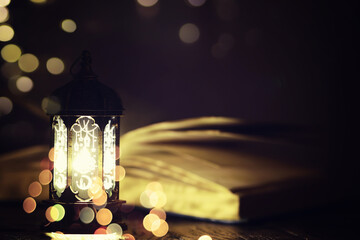 Ramadan Kareem background. Ornamental Arabic lantern glowing and the holy book of Quran.