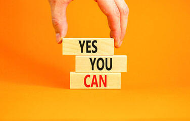 Poster - Motivational and Yes you can symbol. Concept words Yes you can on beautiful wooden blocks. Beautiful orange background. Businessman hand. Business motivational and Yes you can concept. Copy space.