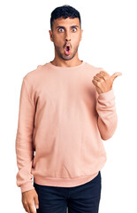 Poster - Young hispanic man wearing casual clothes surprised pointing with hand finger to the side, open mouth amazed expression.