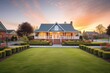 colonial brick house with manicured front lawn at sunrise