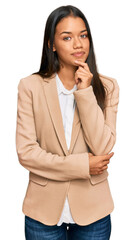 Canvas Print - Beautiful hispanic woman wearing business jacket looking confident at the camera with smile with crossed arms and hand raised on chin. thinking positive.