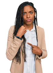 Wall Mural - African american woman wearing business jacket in hurry pointing to watch time, impatience, looking at the camera with relaxed expression