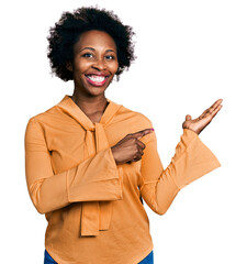 Wall Mural - African american woman with afro hair wearing elegant shirt amazed and smiling to the camera while presenting with hand and pointing with finger.