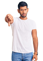 Sticker - Young latin man wearing casual clothes looking unhappy and angry showing rejection and negative with thumbs down gesture. bad expression.