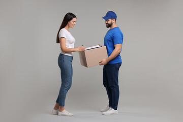 Poster - Smiling woman signing order receipt on grey background. Courier delivery