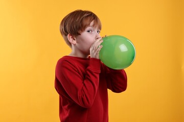 Sticker - Boy inflating green balloon on orange background