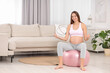 © New Africa - Pregnant woman meditating on fitness ball in room, space for text. Home yoga