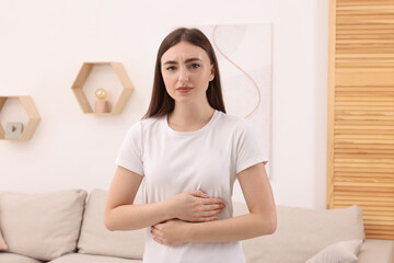 Canvas Print - Young woman suffering from stomach pain at home