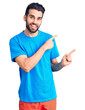 © Krakenimages.com - Young handsome man with beard wearing casual t-shirt smiling and looking at the camera pointing with two hands and fingers to the side.