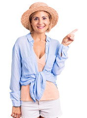 Poster - Young blonde woman wearing summer hat smiling happy pointing with hand and finger to the side