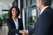 © Rathnayakamudalige - Capturing success: Happy mature Latin businesswoman manager or lawyer confidently handshaking client in office meeting. Smiling professionals sealing a partnership agreement with a firm handshake.