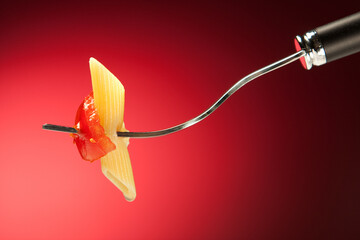 Wall Mural - Fork with pasta and tomato on a red background