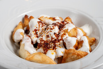 Wall Mural - Turkish ravioli. Ravioli with yoghurt and sauce on a white background. Close up