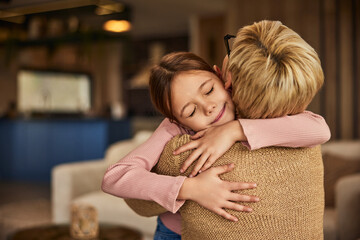 Wall Mural - A photo of a little girl hugging her grandma, keeping her eyes closed, looking cute.