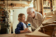 © Marko Geber - Grandfather and grandson working on a model boat in a woodworking workshop
