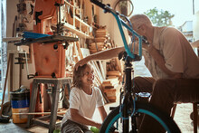 Grandfather And Grandson Fixing A Bike In The Garage