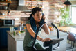 © Marko Geber - Young Asian woman on a exercise bike at home