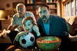 © Marko Geber - Multigenerational group of males watching a football soccer game on the tv in the living room and cheering for their sports team