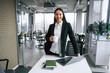 © standret - Standing by the table. Businesswoman is indoors in the office
