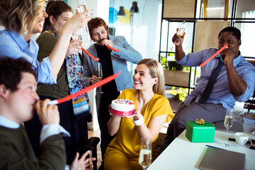 Canvas Print - Young smiling woman holding birthday cake with colleagues in office