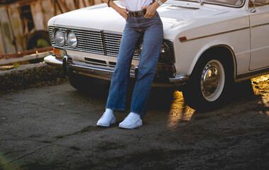 Wall Mural - This image captures a womans lower legs as she is wearing trendy white sneakers paired with classic blue jeans on an urban sidewalk.