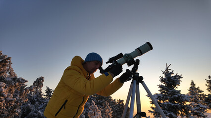 Wall Mural - amateur astronomer looking at the skies with a telescope in winter time.