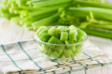 Wall Mural - Fresh celery sliced in bowl with bunch celery on white wooden table.